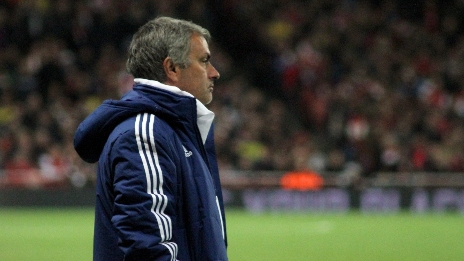 José Mourinho seisoo kentän laidalla sinisessä talvitakissa ja katsoo sivulle, taustalla katsomo.
